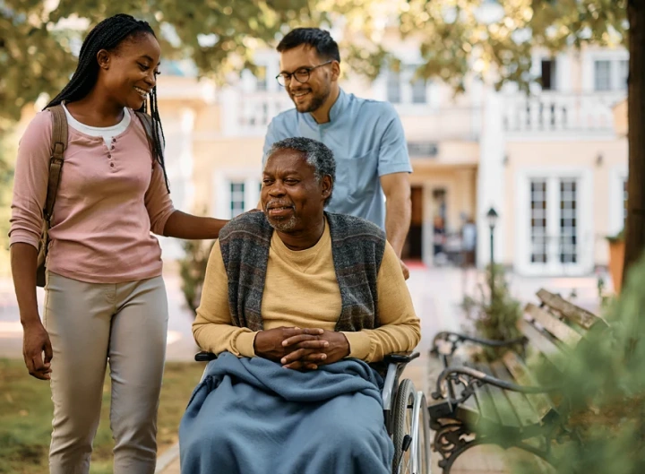 An elderly man on wheelchair with a boy and a girl