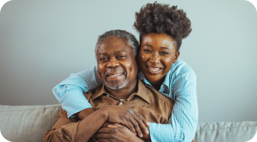 A lady hugging an elderly man from the back